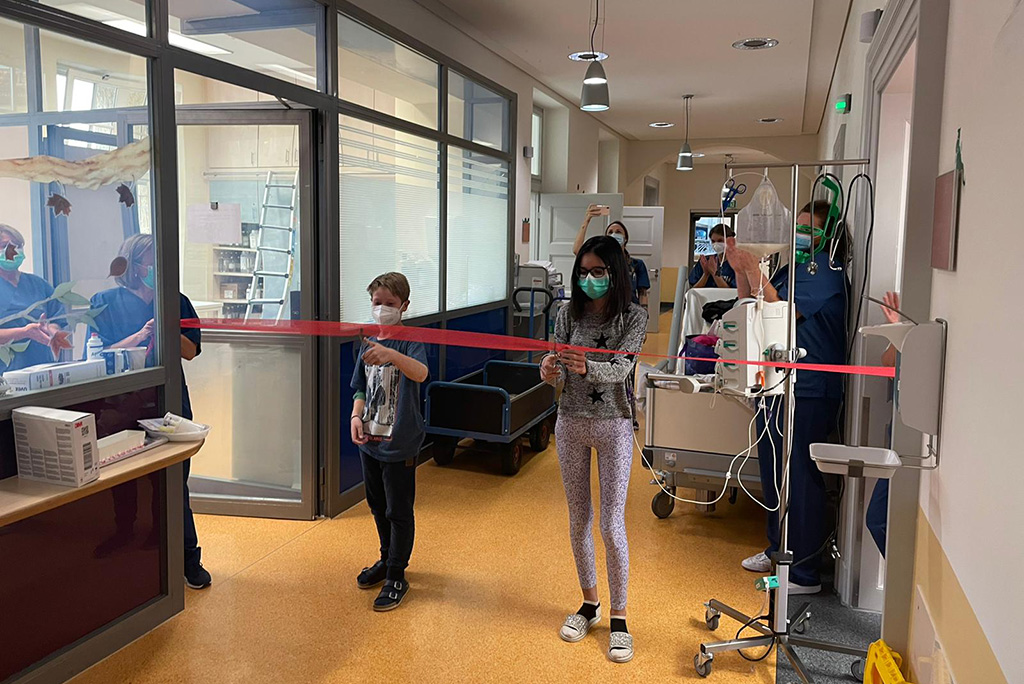 Kinder schneiden zur Wiedereröffnung ein rotes Band durch