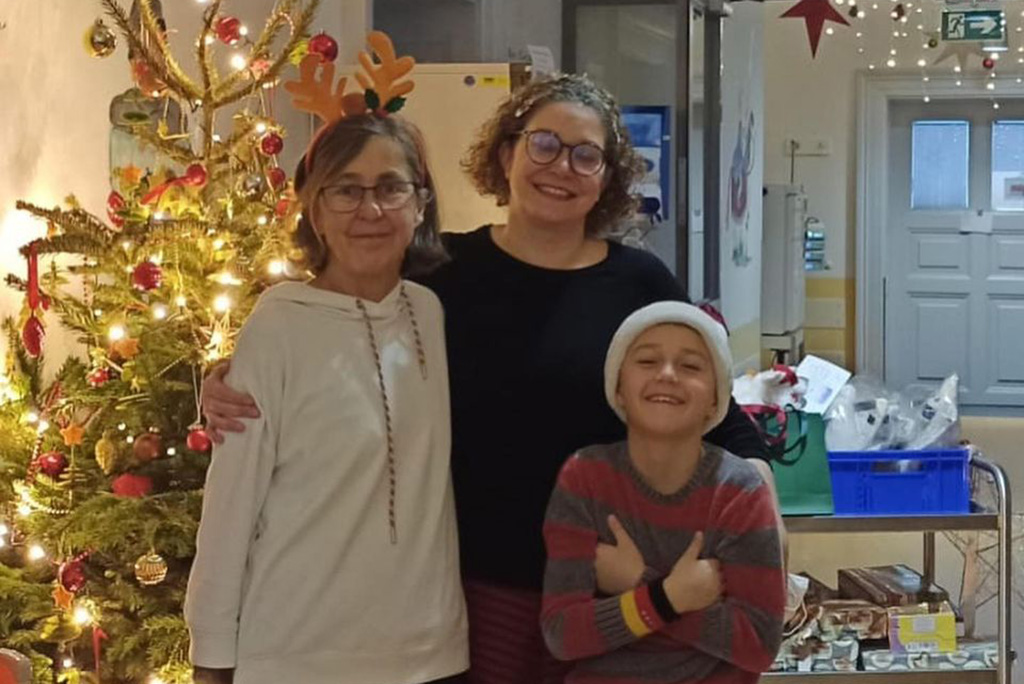 Kind, Mutter und Betreuerin vor Weihnachtsbaum