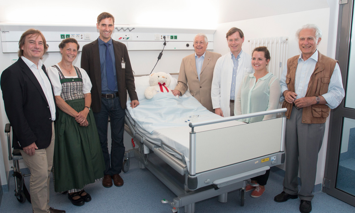 Mitarbeiter des Süßwarenverbands Sweets Global Network e.V. und Kinderklinikmitarbeiter vor einem Krankenbett