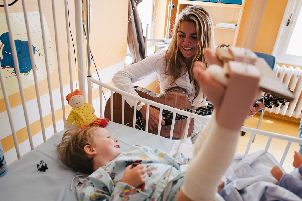 Frau Birger beim Gitarre spielen am Krankenbett eines Mädchens