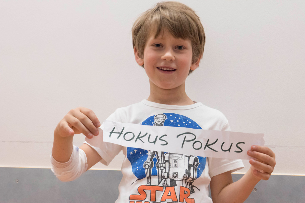 Junge mit Papier in der Hand auf dem Hokus Pokus steht