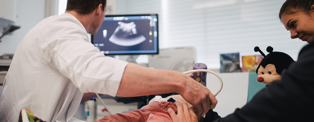 Arzt bei der Ultraschall-Untersuchung bei einem Kind
